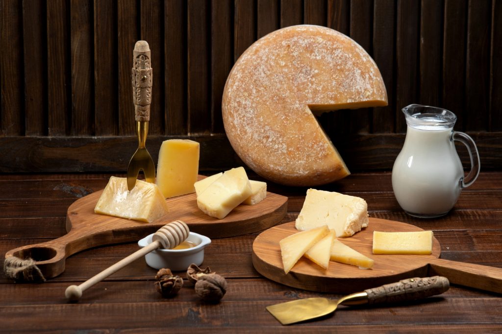 Multiple types of cheese with a wooden themed background